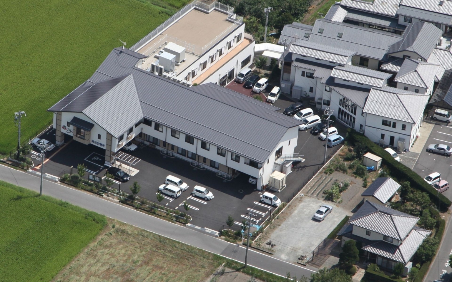 介護施設の空撮写真。駐車場と周辺建物が見える全体像